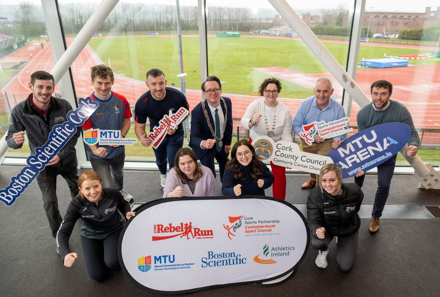 Photo of people in a running pose surrounding the Rebel Run banner